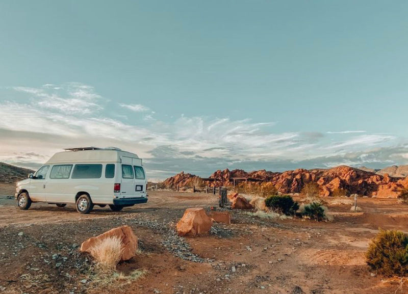 White RV rental camper van parked at a desert campsite, surrounded by red rock formations and a vast sky. — photo 12