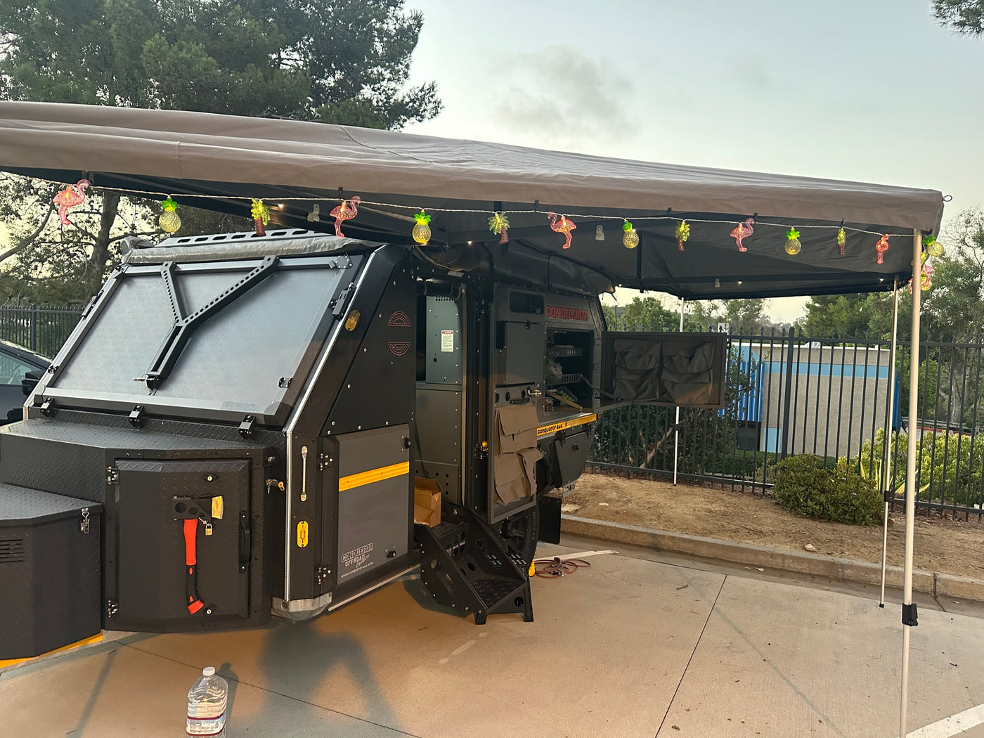 Rugged Conqueror 4x4 off-road camper with tropical lights under the awning, great for RV rental adventures. — photo 3