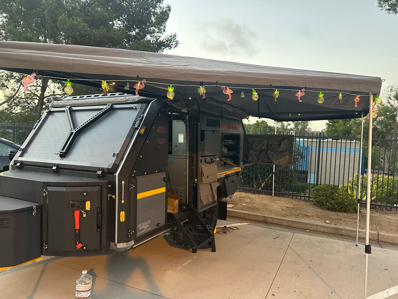 Rugged Conqueror 4x4 off-road camper with tropical lights under the awning, great for RV rental adventures. — photo 3