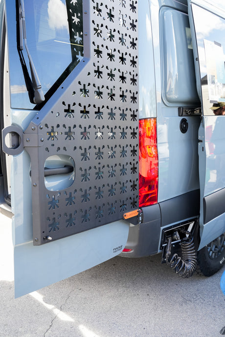 Rear of a customized grey van, featuring a gear mounting panel and an outdoor shower, ideal for an rv rental adventure. TYACKE MOTORS.