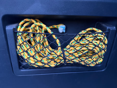 Coiled yellow, green, and black rope in a dark mesh storage net, a common organizational feature in an RV rental.