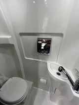 Compact RV rental bathroom with white toilet, sink, and wall-mounted dispenser. Efficient use of space.