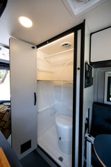 RV rental: Bright, compact wet bath in a camper van, showing a toilet, shower area, and clean interior.