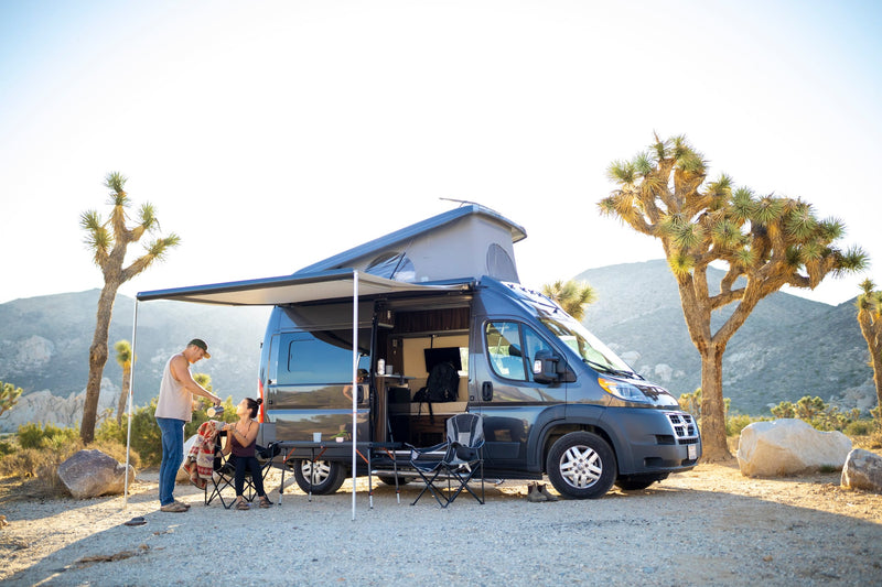 Serene desert camping with an RV rental. Couple enjoys coffee by their camper van — photo 1