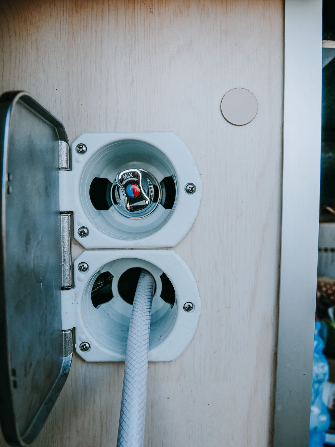 RV rental's external water hookup: an outdoor shower with mixer and connected hose for convenient use.