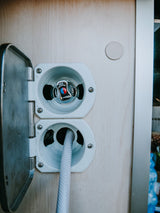 RV rental's external water hookup: an outdoor shower with mixer and connected hose for convenient use.