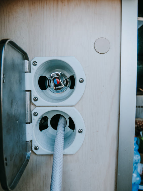 RV rental's external water hookup: an outdoor shower with mixer and connected hose for convenient use.