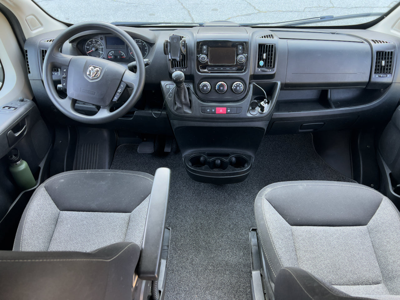 Front cabin view of an RV rental, featuring driver's controls, dashboard, and two comfortable seats.