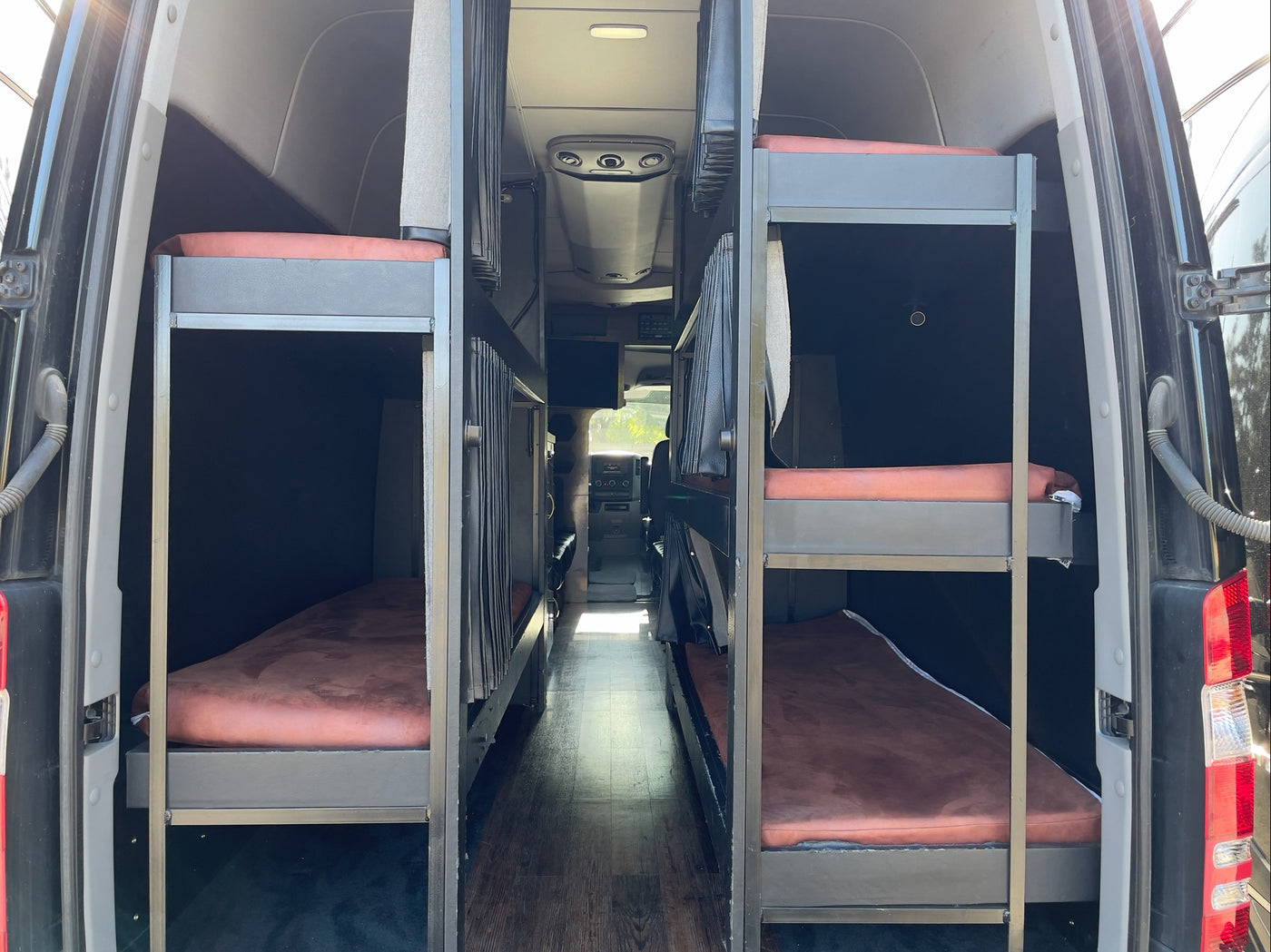 Spacious RV rental interior featuring two sets of bunk beds along a central aisle, ideal for group travel. — photo 3