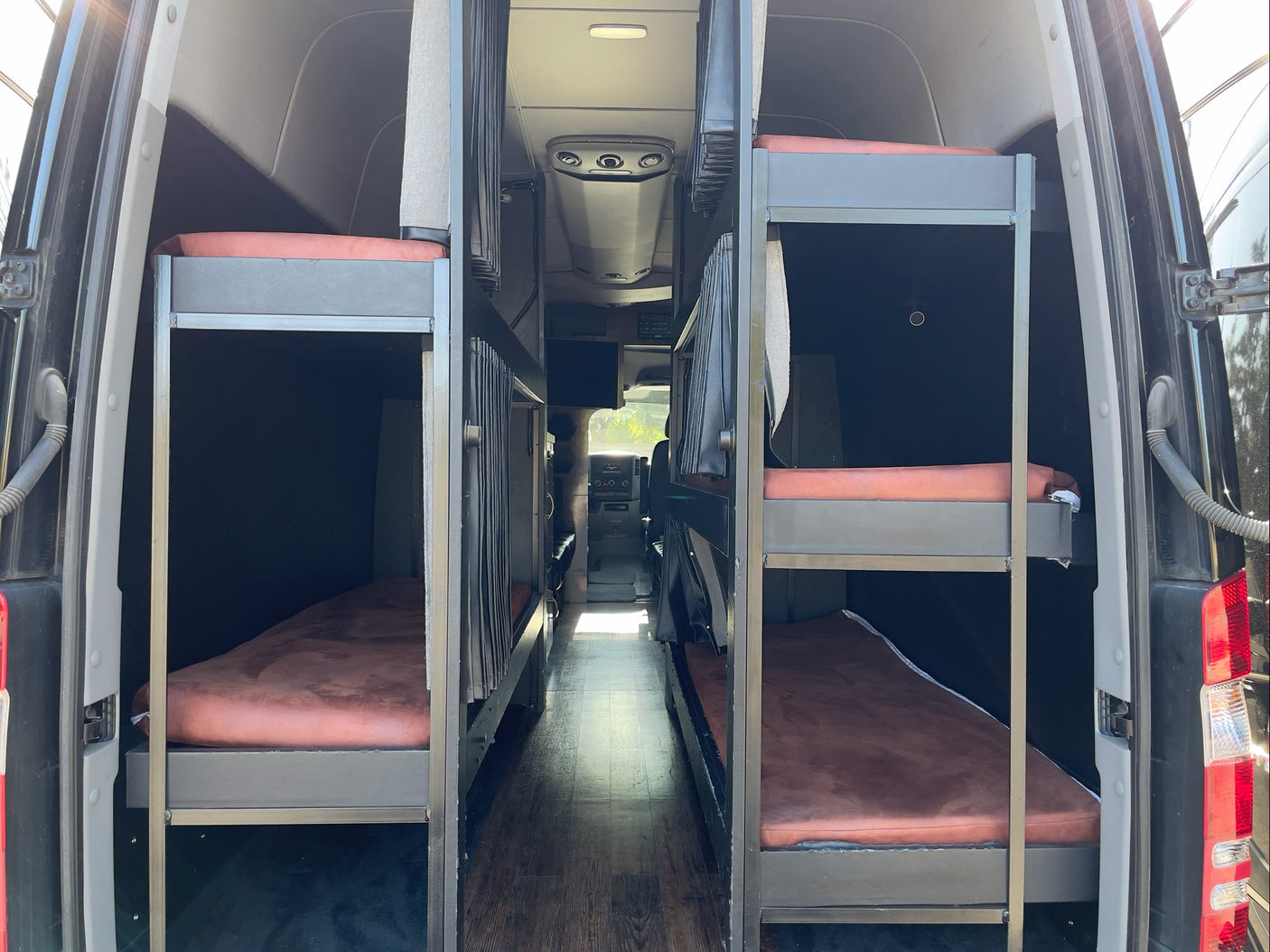 Spacious RV rental interior featuring two sets of bunk beds along a central aisle, ideal for group travel.