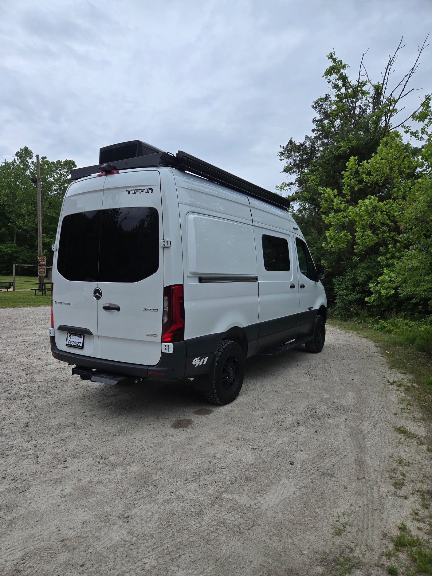 White Tiffin Sprinter RV rental, equipped with an awning and roof AC, on a dirt road. Perfect for adventure travel.