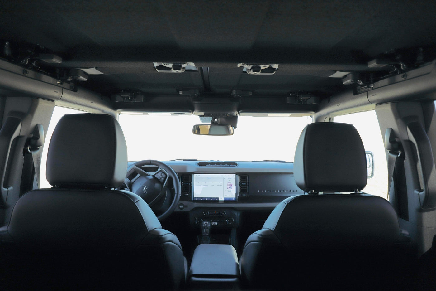 RV rental adventure: Ford Bronco interior from rear seats, featuring dashboard, steering wheel, and roof latches. — photo 4
