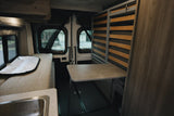 RV rental interior: cozy camper van with convertible bench bed, fold-down table, and a small sink for mobile living.