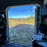 An RV rental provides this incredible view of snow-capped mountains from its open doors, blending comfort with nature.