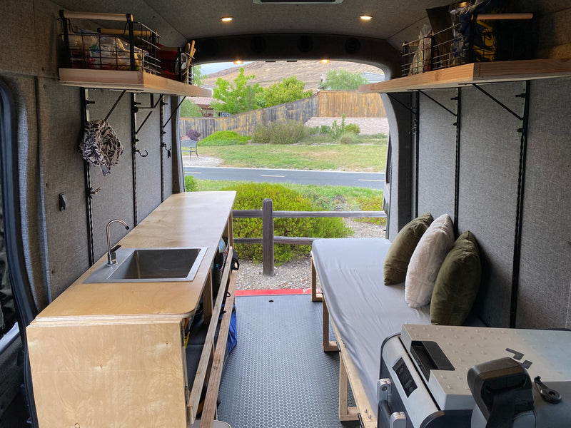 Bright RV rental interior: kitchenette with sink, cozy bed, and organized storage. Scenic outdoor view. — photo 6