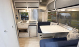 Modern rv rental interior with compact kitchen, cozy dinette, and sleek design, perfect for travel trailer adventures.