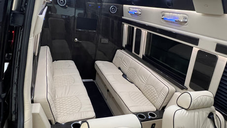 A plush **rv rental** interior showcases quilted cream benches, dark wood accents, and ambient lighting, offering luxurious travel comfort.