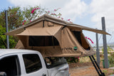 Tan rooftop tent on a white pickup truck.