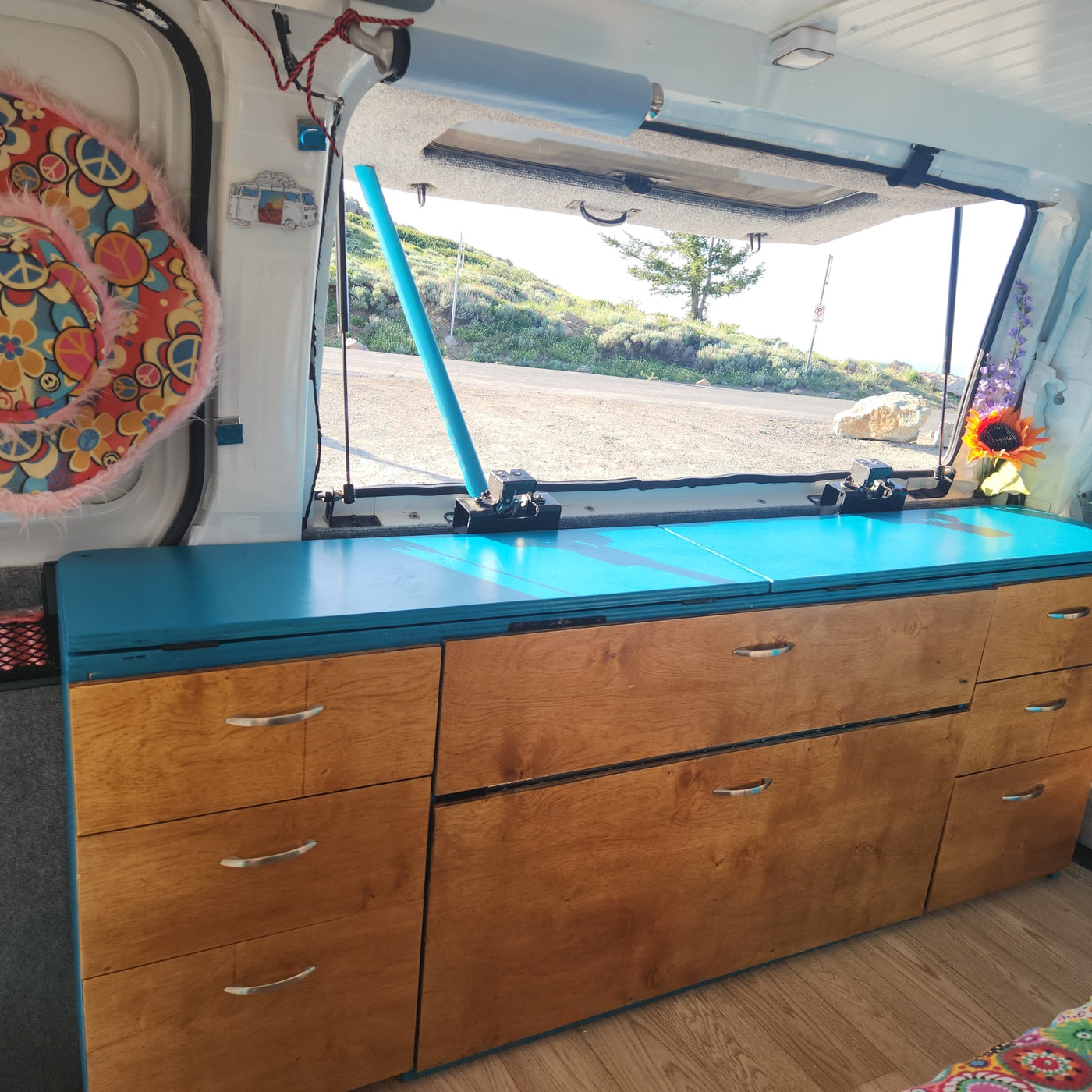 Inside an **rv rental**: custom wood & blue storage, open hatch with scenic outdoor view. — photo 19