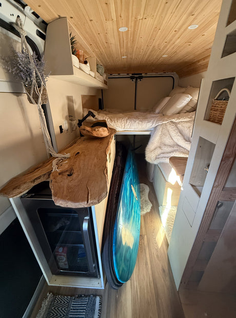 Inside this **rv rental**: wood ceiling, comfy bed, live-edge counter, mini-fridge, and surfboard storage. Perfect for a cozy road trip.