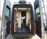 Inside an rv rental camper van: rear view showcasing open doors, adaptable living space with storage, and front cabin.