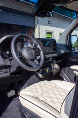 Driver's view of a luxury Mercedes-Benz Sprinter RV rental, featuring a modern dashboard and quilted cream leather seat.