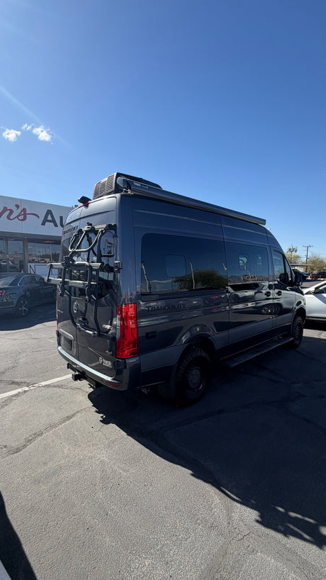 Dark gray Mercedes Sprinter Thor Tranquility rv rental camper van with a bike rack, parked outdoors on a sunny day.