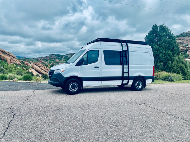 Scenic RV rental, a white Sprinter van, parked on an asphalt road with red rocks and cloudy skies in the background. — photo 6