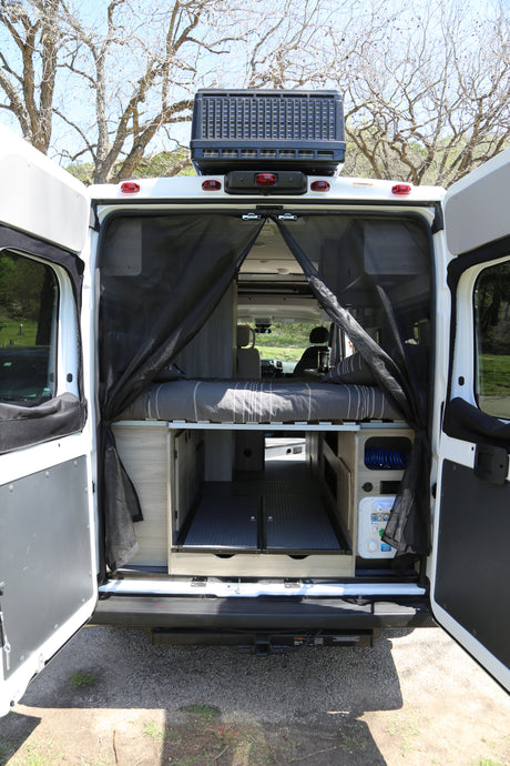 This RV rental's rear offers a comfy bed, pull-out storage, and mesh screen, ideal for camping and road trips.