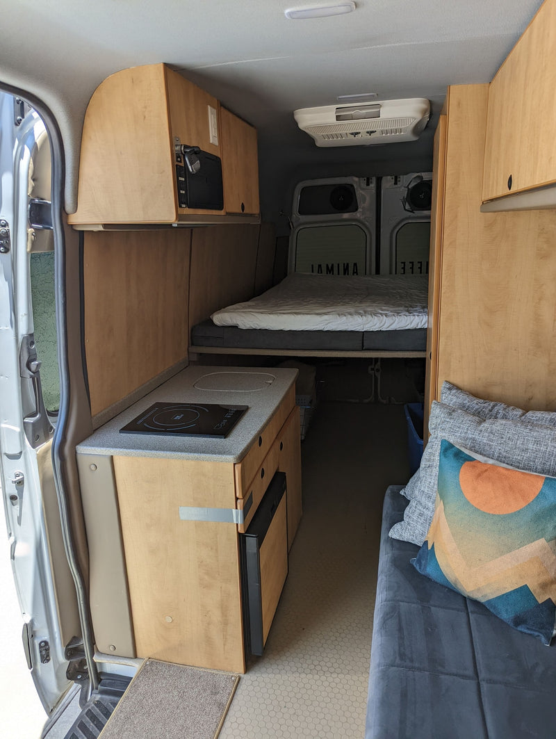 Explore this comfy RV rental camper van interior. Features a kitchen, bed, and cozy living area, perfect for road trips. — photo 19