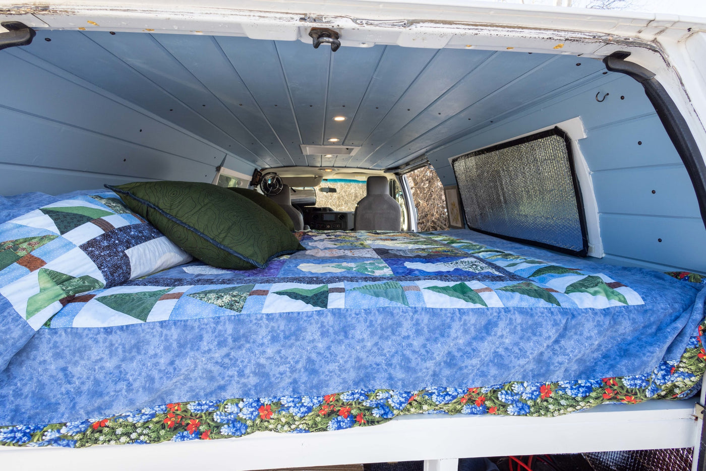 and a forest view from the side window of this camper van.|View inside a cozy RV rental: custom camper van with a bed — photo 9