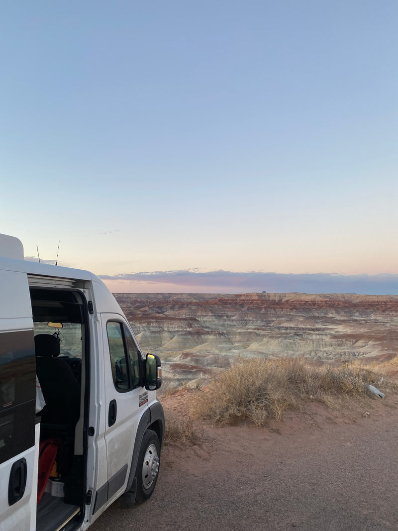 An rv rental campervan offers a stunning view of a layered desert badlands landscape under a soft, morning sky. — photo 17
