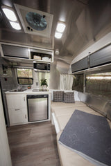 Inside this RV rental: a streamlined kitchen with fridge & microwave, plus a comfortable convertible bed. Ideal for road trips.