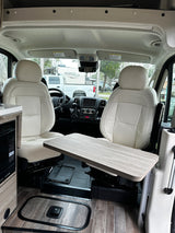 Modern rv rental interior features cream seats, a functional table, and wood-look flooring for comfortable travel.