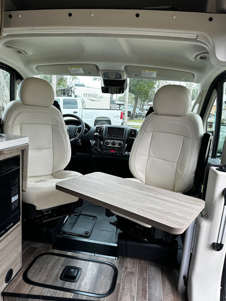 Modern rv rental interior features cream seats, a functional table, and wood-look flooring for comfortable travel.