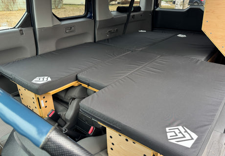 Honda Element camper bed conversion for comfortable car camping or an RV rental alternative. Black mattresses, wooden supports.