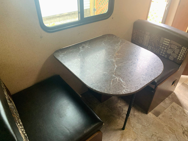 Compact RV rental dinette with dark benches, marbled table, and window view for road trips. — photo 6