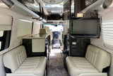 Spacious RV rental interior featuring comfortable seating, a compact kitchen, and TV for enjoyable travels.