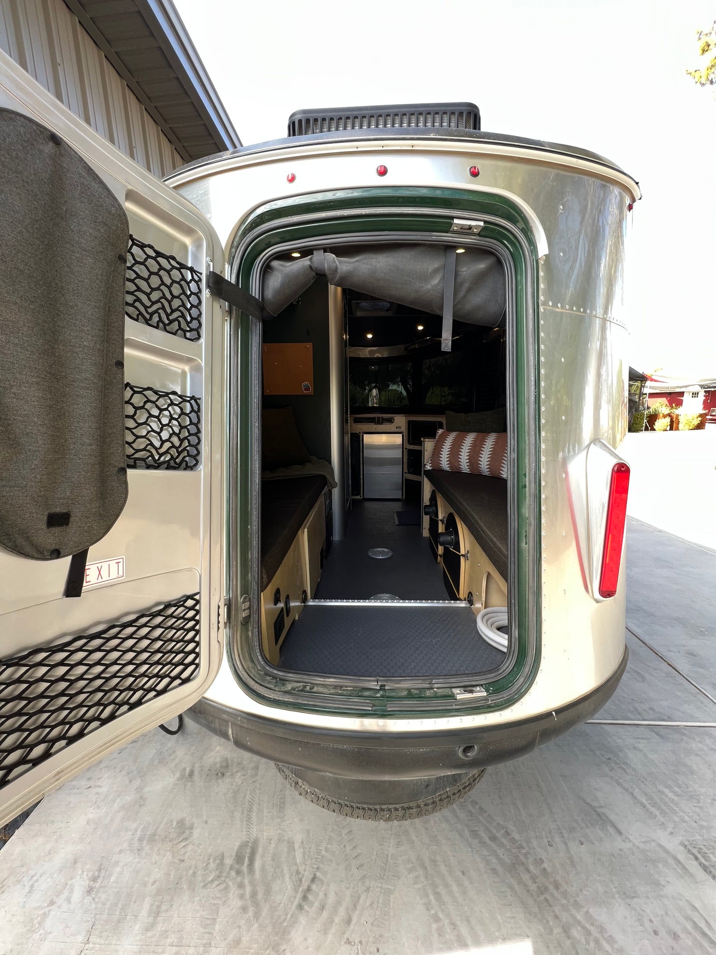 Step inside this modern rv rental! View of a compact travel trailer interior with beds, mini-fridge, and door storage.