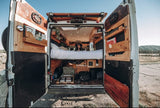 Experience van life! Rv rental campervan's custom interior: elevated bed, storage, open doors to nature for travel.
