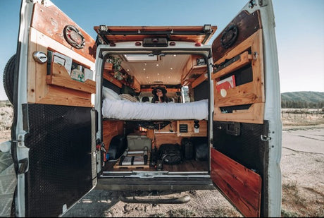 Experience van life! Rv rental campervan's custom interior: elevated bed, storage, open doors to nature for travel.