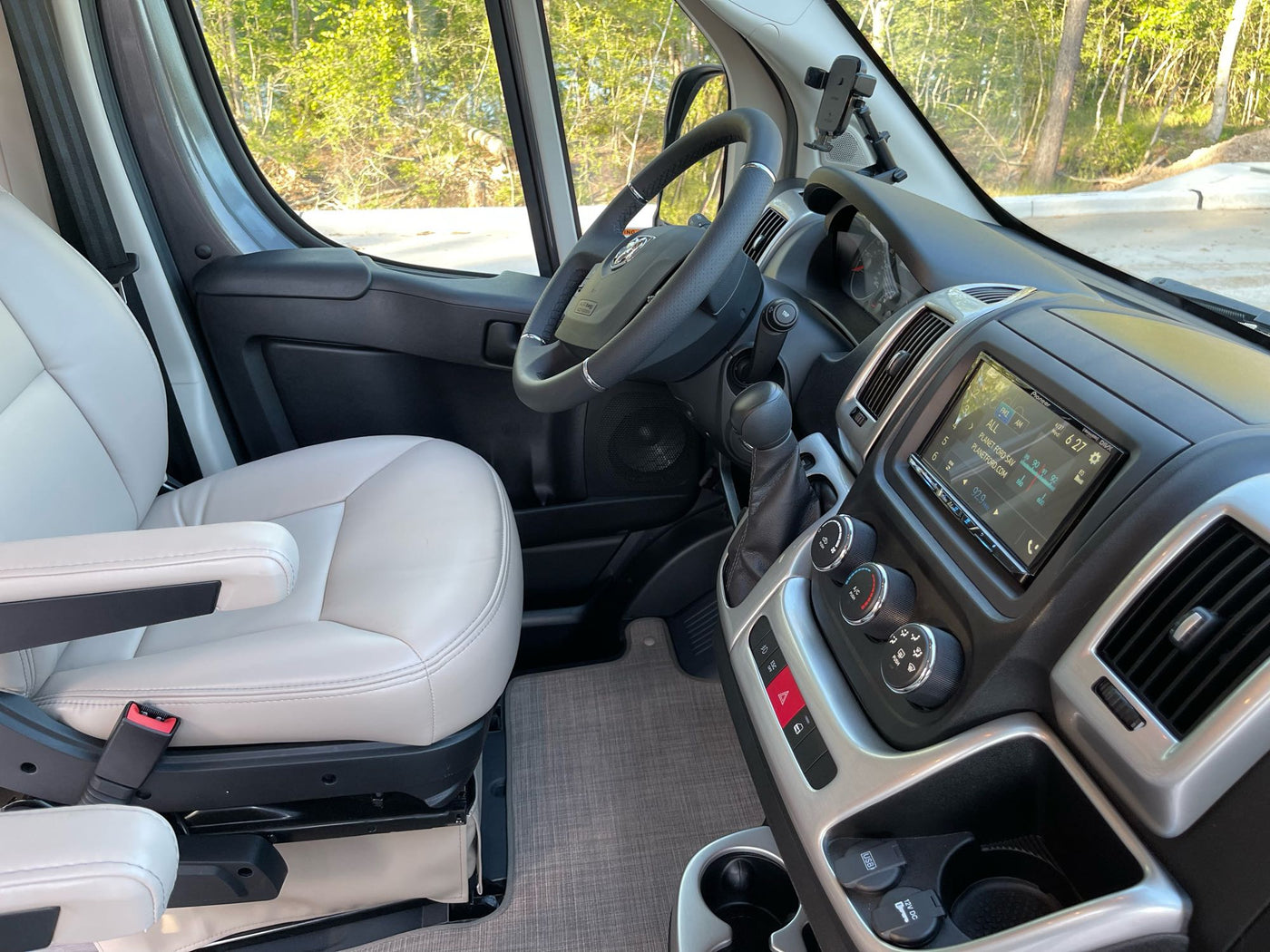 Step inside this RV rental! View of a modern camper van cockpit with beige seats, steering wheel, and tech-filled dashboard. — photo 6