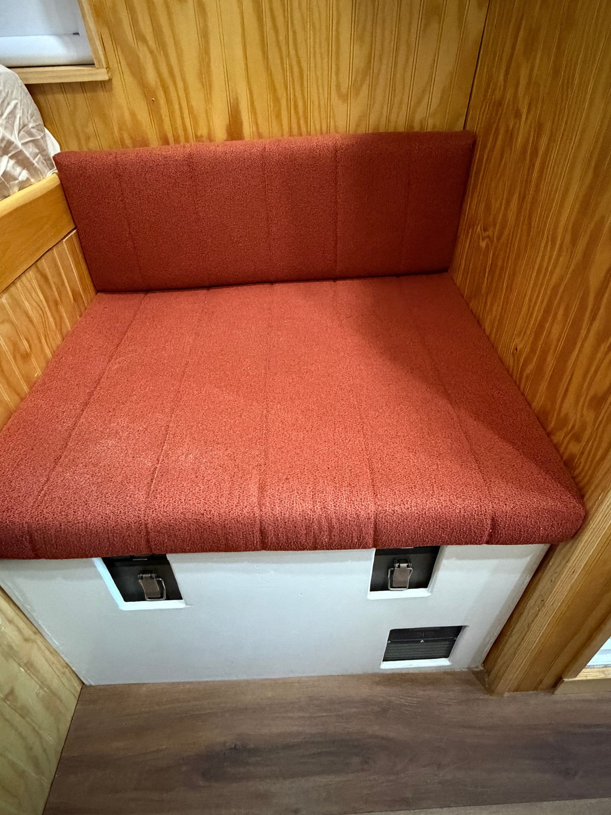 Cozy orange cushioned bench and backrest in an rv rental, featuring wood paneling & under-seat storage with latches. — photo 15