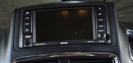 An RV rental's black car stereo/infotainment system with a blank screen, USB, AUX, and control buttons for media, radio, and volume.