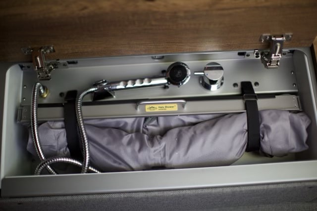 This rv rental features a compact Halo Shower system with a shower head, faucet, and neatly stowed portable enclosure.