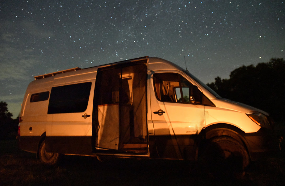 Experience adventure under the stars with this RV rental camper van. White van, open side door, interior visible, against a clear night sky. — photo 13