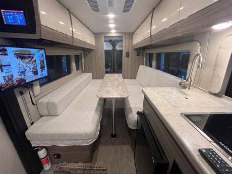 Modern RV rental interior: dining area, compact kitchen, and smart controls for comfortable travel.