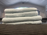 Light blue towels stacked on a dark bed inside an RV rental, set for comfort on your journey.
