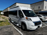 Bright white Ram ProMaster RV rental van, featuring an awning, parked under a clear sky.