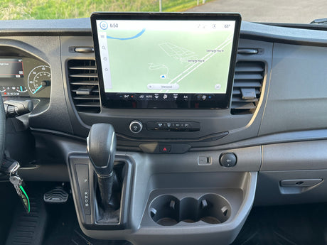 Interior of an RV rental showing the dashboard with a large infotainment screen displaying a map, climate controls, and gear shifter.